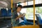 Young man sitting in city bus and reading a book.