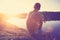 Young man sitting on the cliff near river and looking far away at sunset