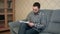 Young man sitting on the couch making some notes in the textbook