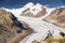 Young man sitting and enjoying a majestic view to Aletsch glacier, the largest gracier in Alps and UNESCO herritage from