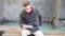 Young man sitting by fountain reading paper sheets in city setting