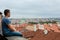A young man sitting in front of Prague tiled roofs. Czech