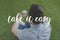 young man sitting on grass with cup on coffee to go take it