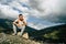 Young man sitting on hill. Dreamy male sitting on altitude and looking at Peaks of magnificent rocks located against