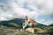 Young man sitting on hill. Dreamy male sitting on altitude and looking at Peaks of magnificent rocks located against