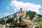 Young man sitting on hill. Dreamy male sitting on altitude and looking at Peaks of magnificent rocks located against