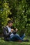 Young man sitting on a park while watching his computer and celebrating furiously with his hands. Natural Environment. Vertical