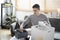 Young man sitting on sofa preparing personal stuff for moving into new house.