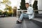 Young man sitting on stairs alone on street and working on laptop