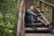 Young man sitting on stairs in forest