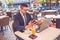 Young man sitting at street cafe having a conversation on a laptop  wearing a headphones on head talking looks angry