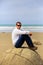 Young man sitting on top of one Moeraki Boulder