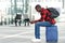 Young man sitting on traveling bag and using cell phone