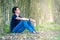 Young man sitting by a tree in the woods thinking about life and resting. copy space