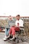 Young man sitting in the wheelchair and looking at laptop