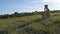 Young man sitting in yoga pose at green grass in the meadow and meditates. Muscular guy relaxing in lotus pose at nature