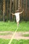 young man is slacklining walking and balancing on a rope, slackline outdoors