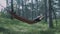 A young man is sleeping on a hammock in the forest. The tourist is resting on a hammock.