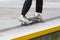 Young man slides on skateboard along metal edge of concrete ramp in skate park