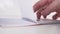 A young man slowly leafs through a notebook with spiral horizontal pages fastening on a white background