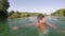 Young man smiling and shaking water off his head in river