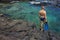 Young man with snorkeling equipment on the rock coast