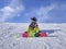 Young man - snowboarder sitting on the top of the mountain admiring the view over clouds. Sitting above the clouds