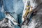 Young man solo ice climbing a short gradual slope next to a large ice cave