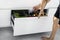 A young man sorts garbage in containers in the kitchen in slow motion. Modern kitchen with a system for sorting waste