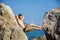 Young Man Spanning Gap Between Coastal Boulders