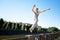 Young man in sportswear jumping and practicing parkour outside on stone fence over river embankment on clear summer day