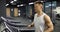 Young man in sportswear runs on treadmill in gym