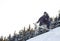 Young man in sportswear snowboarding over pine trees background