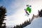 Young man in sportswear snowboarding over pine trees background