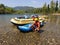 A young man squatting near an inflatable boat rafting along a mo