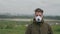 Young man is standing on a city background, in dense smog in a medical mask.