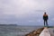 Young man standing on the edge wharf and watching mountains on other side. Man is standing on the edge of Ayia napa city which is