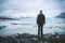 Young man standing in front of Fjallsarlon iceberg lagoon at the south end of the glacier Vatnajokull, with floating