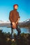 Young man is standing with a guitar on background of mountains and lake. Place for text or advertising