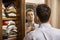 Young man standing in his bedroom dressing at mirror
