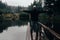 Young man standing on loodgate pond in rainy weather. Natural reserve Czech canada, dark mood green