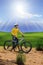young man standing beside moutain bike ,mtb on hill with sun shining on blue sky use for sport leisure and out door activities ex