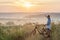 Young man standing near bicycle in morning sunrise with wonderf