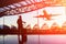 Young man is standing near window at the airport and watching plane before departure. She is standing and carrying luggage