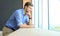 Young man standing near window in his office while thinking about his goals.