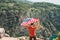 Young man standing on a rock cliff and waving the US flag while looking at sea beneath. Veteran traveller waving the