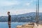 Young man standing on sea pier in harbor and looking ahead. Seagulls and gulls in sky. Mediterranean line, Palamos, Costa Brava,