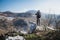 Young man standing on top of cliff in winter mountains holding a