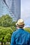 Young man stands and looks at the office building and thinks about work and career. Back view of a man in a hat.