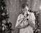 Young man stands near Christmas tree and kisses puppy of dalmatian dog